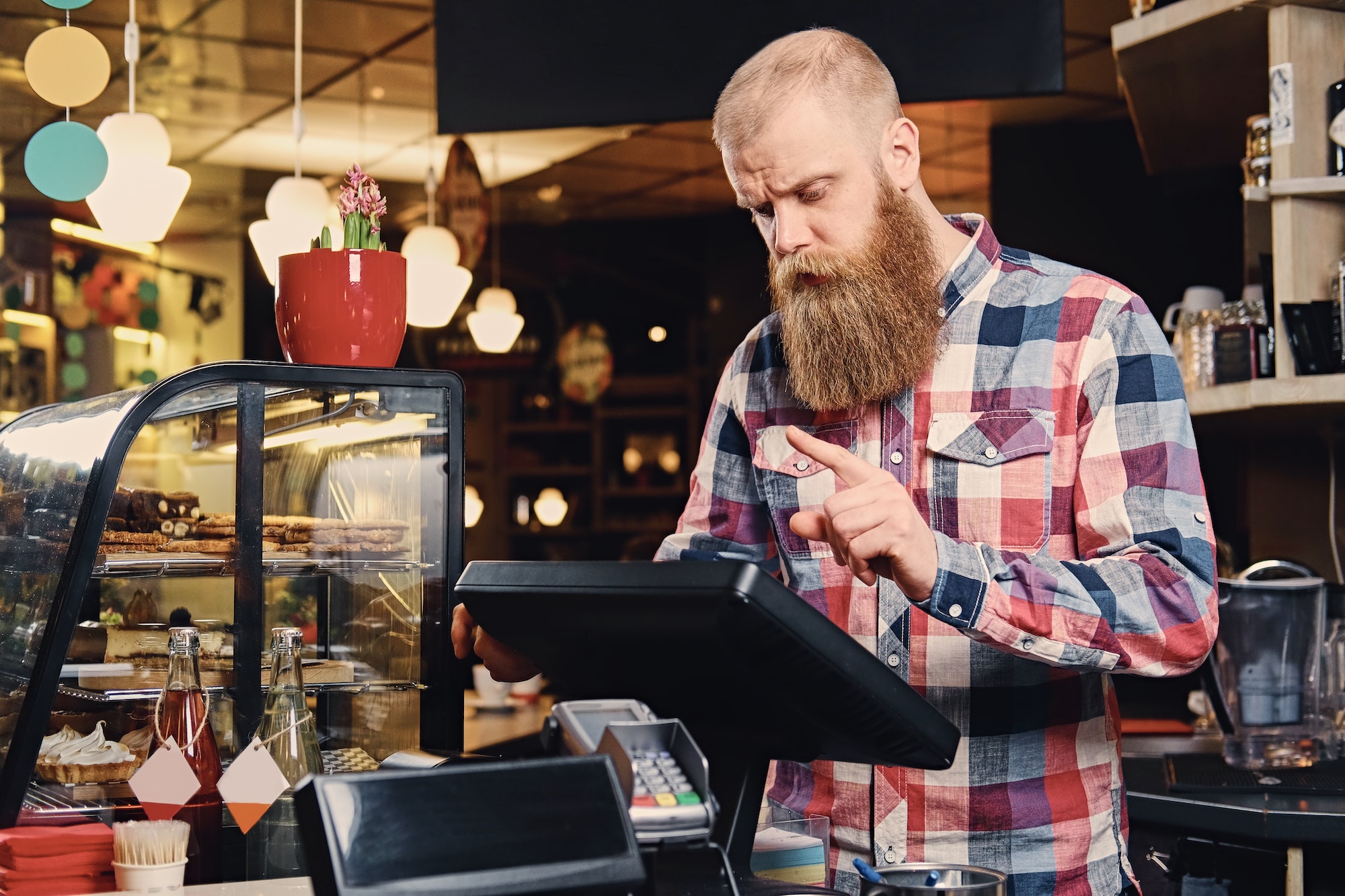 A man at the counter using cash register in a coffee shop.